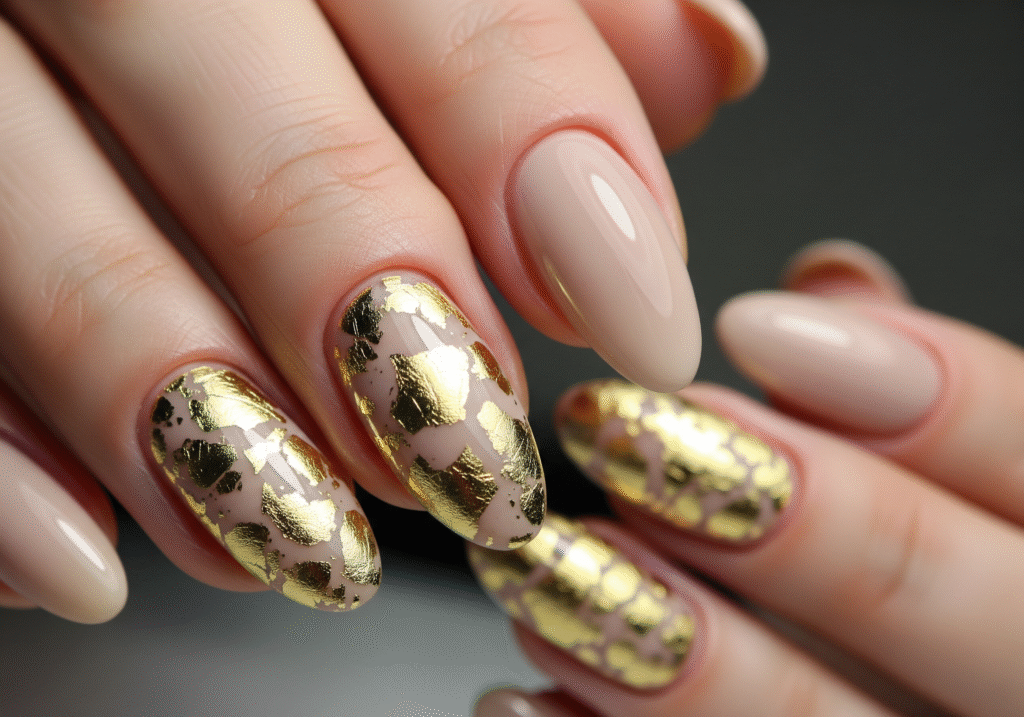 Beige nails with gold foil pieces on accent nails.